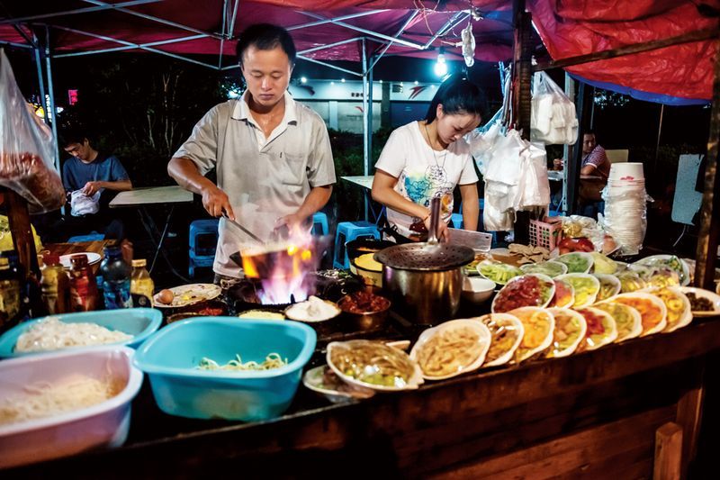 A couple busy with their stir-fry stand serve late-night customers