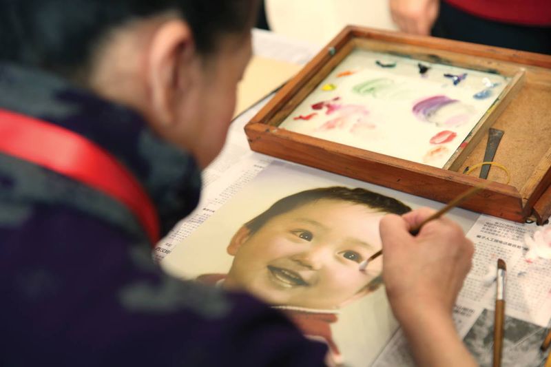 A photo artist at CPS coloring a black-and-white photo