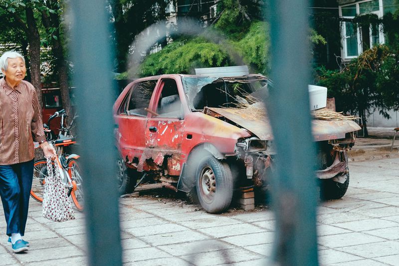 A woman walks part a local relic —a scrapped Xiali model taxi cab