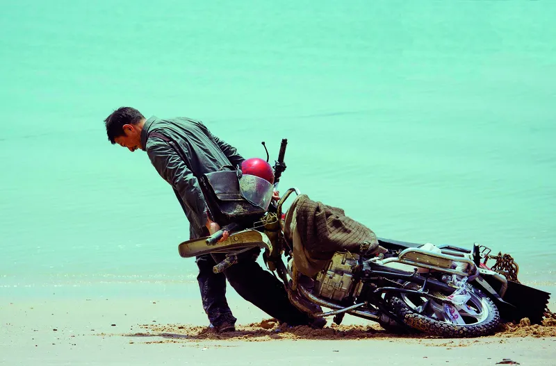 Lei pulling his motorcycle from the sea, A scene from the movie Lost and Love