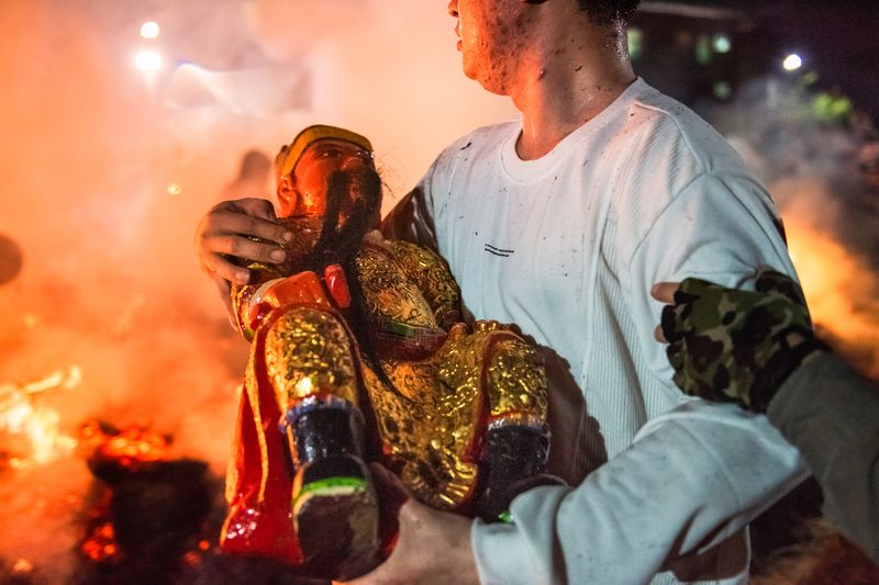 The ritual is in full swing when the statue is taken off the sedan and carried in turn by different young men to run through the flames several times