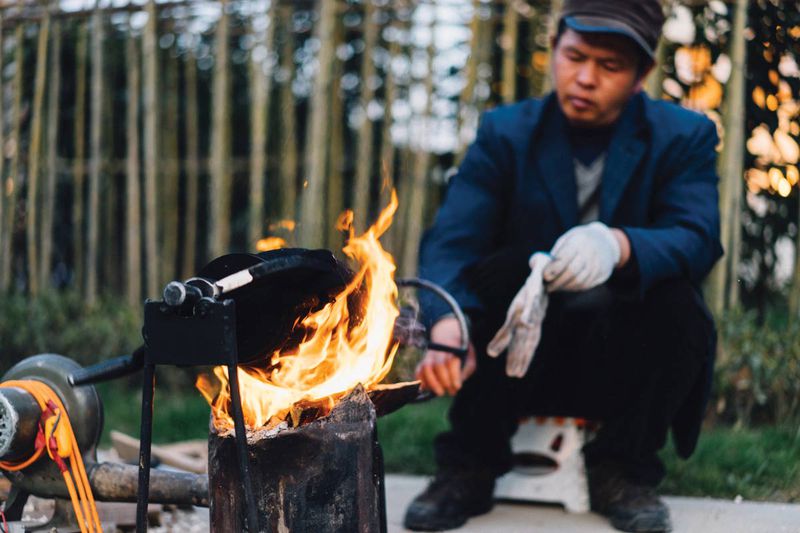 The popcorn vendor rolls the cooker over a fire to build up the pressure inside