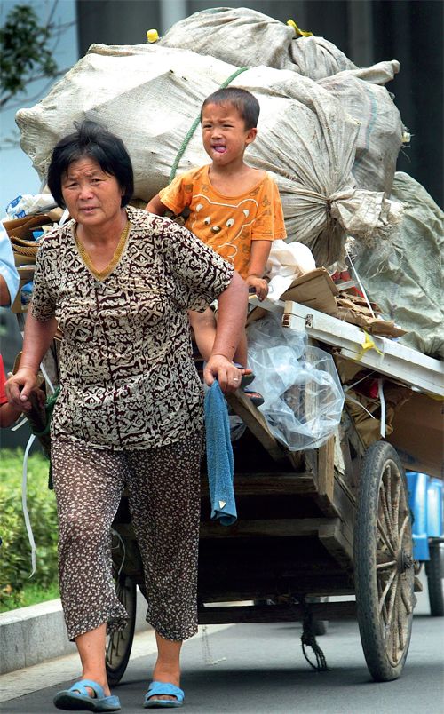 A woman pulls a cart of recyclables by hand through the streets of Nanjing