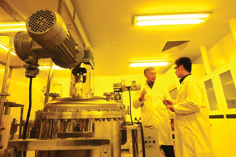 Returned scientist Dr. Sam Xunyun Sun (left) discusses the production of photoresist with research staff