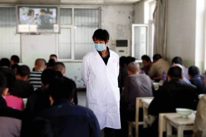 A doctor on patrol, as patients have lunch at a mental hospital in Shanxi province