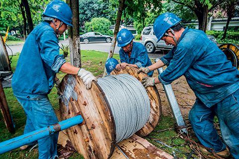 A heavy roll of wire is moved to the site for the workers to use in their repairs