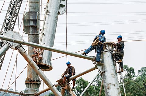 Specialized high-altitude-operation technicians draw wires to the pylons