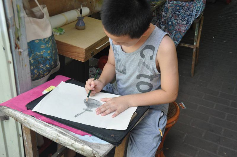 A shop owner&#x27;s son sketches in front of the gallery
