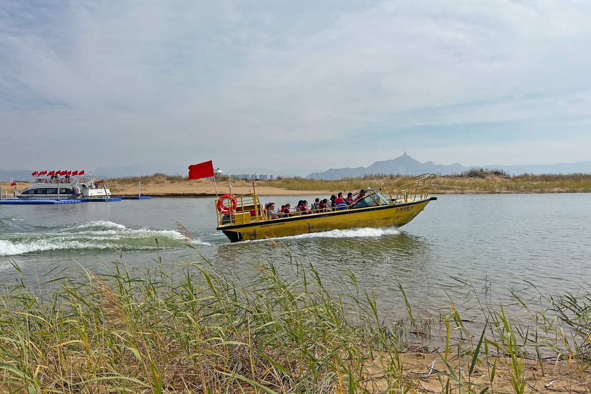 Tourists board sightseeing boats to travel from the lake’s eastern bank in the city to its western bank in the desert. In the distance, a giant Genghis Khan bust tops a mountain.