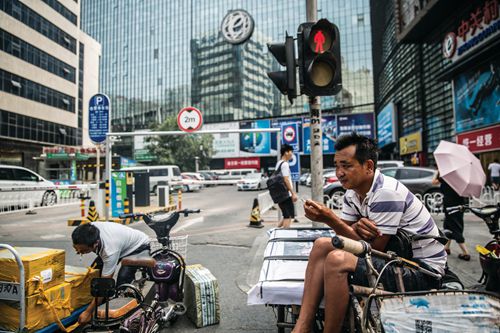 For a decade, Wang (right) has worked around Zhongguancun delivering electronics. “There used to be over 30 tricycle-delivery workers, now over half of them are gone,” he says
